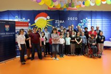 Zima z Uśmiechem 2020 Grupowa fotografia niepełnosprawnych uczniów, kadry pedagogicznej oraz zaproszonych gości, w tle balony oraz ozdoby 